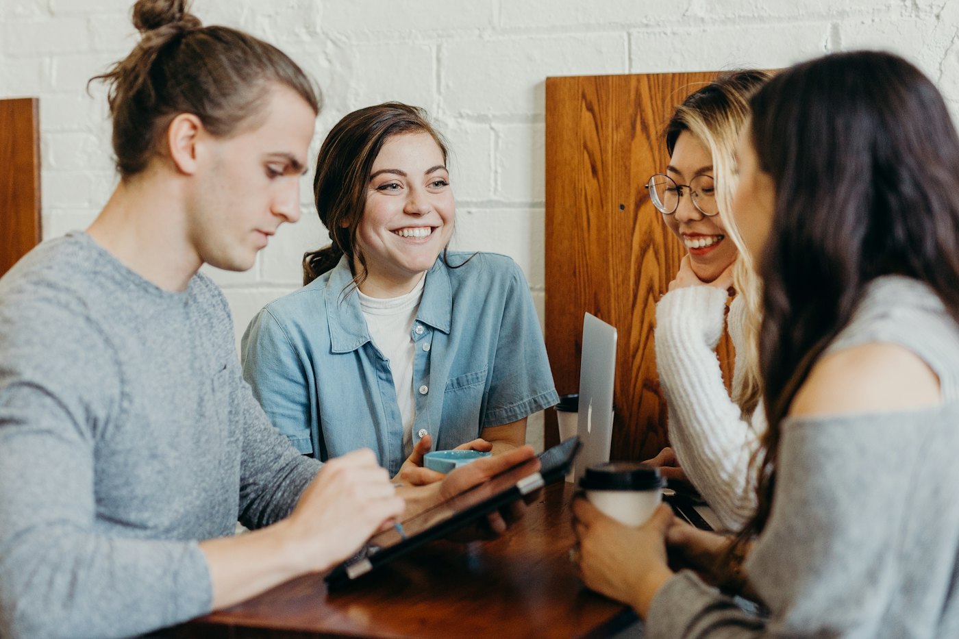 Cuatro personas conversan en una mesa, con café