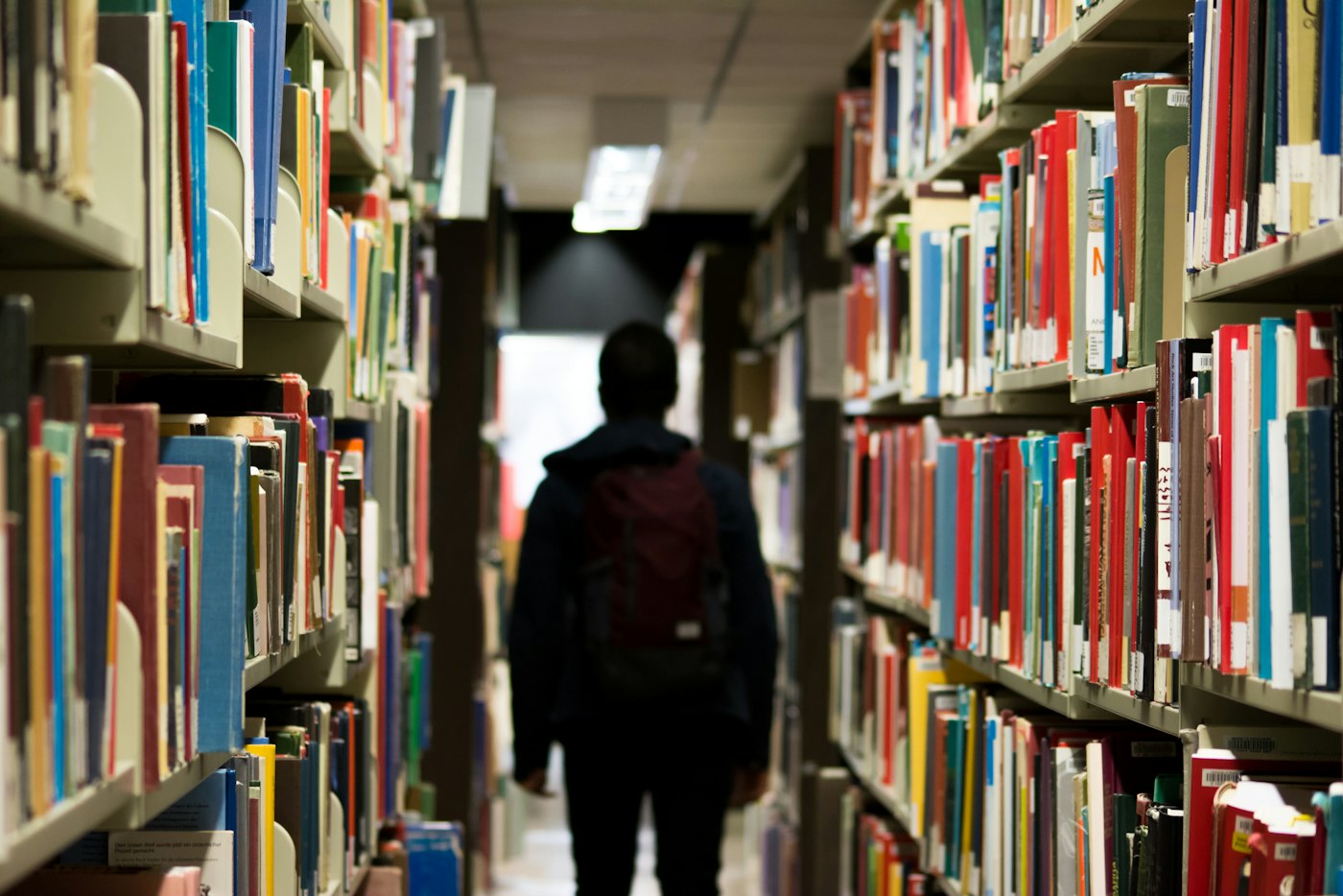 Una persona camina entre estantes de una biblioteca