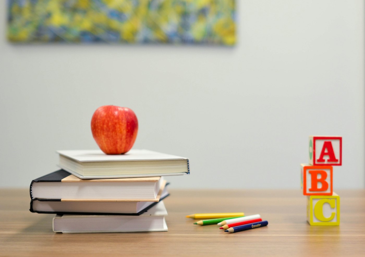 Una manzana sobre unos libros, junto a cubos con letras
