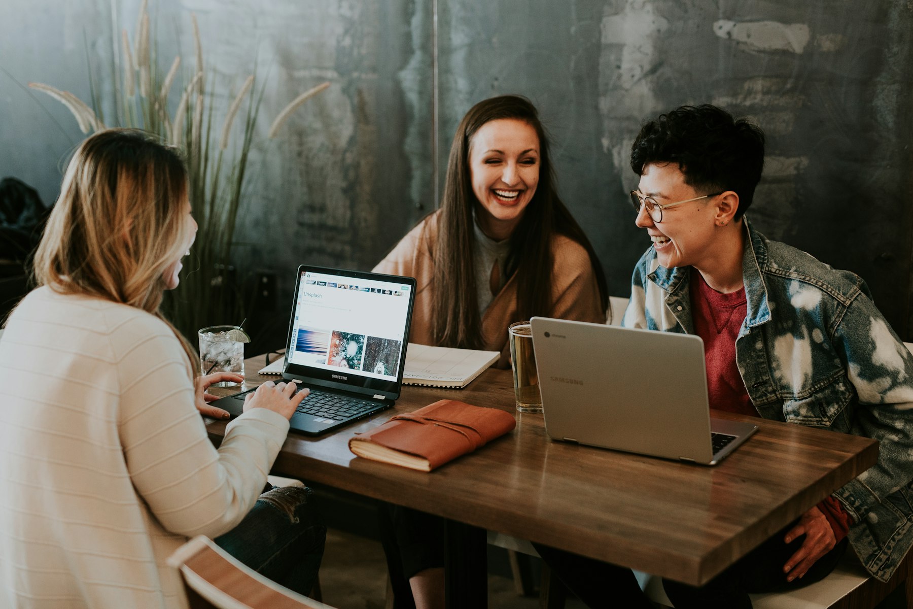 Tres personas conversan alrededor de una mesa con notebooks