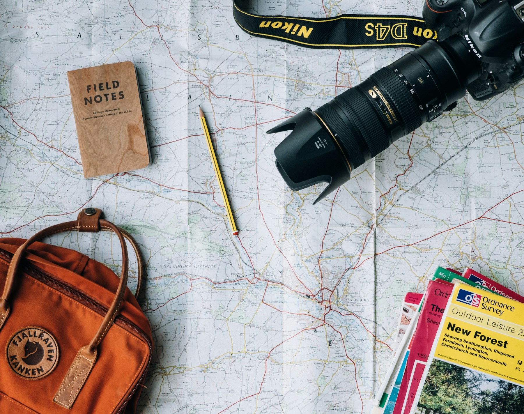 Un mapa, una cámara y una mochila sobre la mesa